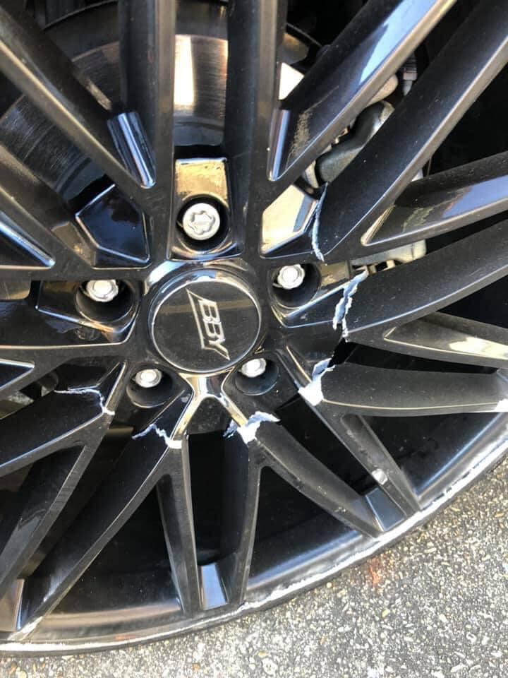 Close-up of kerb rash damage on alloy wheel before repair
