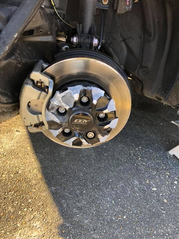 Wheel removed from car for professional straightening service